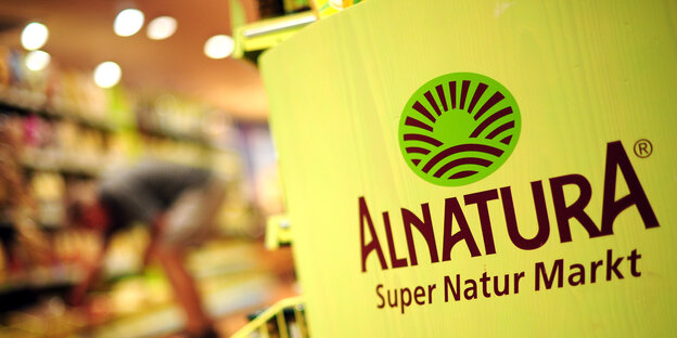 Man sieht das Firmenlogo von Alnatura, im Hintergrund Regale Man sieht das Firmenlogo von Alnatura, im Hintergrund Regale