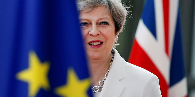 Theresa May steht zwischen einer Flagge der Europäischen Union und einer Flagge von Großbritannien Theresa May steht zwischen einer Flagge der Europäischen Union und einer Flagge von Großbritannien