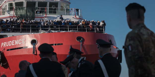 Flüchtlinge auf einem Schiff, Polizisten im Hafen Flüchtlinge auf einem Schiff, Polizisten im Hafen