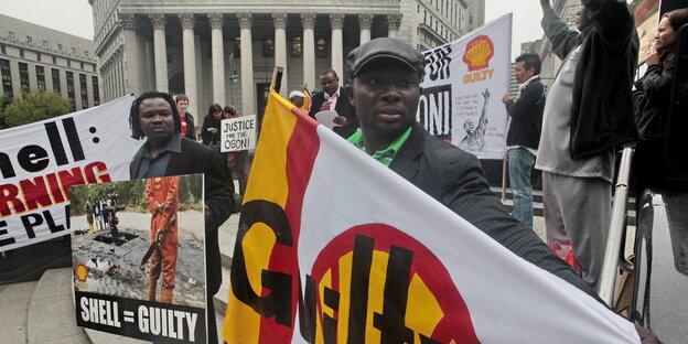 Menschen halten Transparente gegen Shell in den Händen Menschen halten Transparente gegen Shell in den Händen
