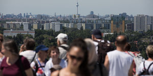 Menschen gucken auf den in der Ferne stehenden Fernsehturm am Alexanderplatz.