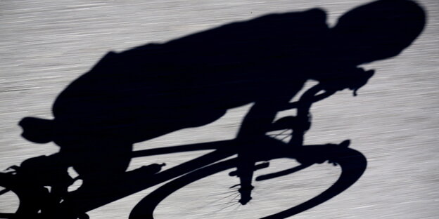 Man sieht den Schatten eines Radfahrers auf Asphalt Man sieht den Schatten eines Radfahrers auf Asphalt