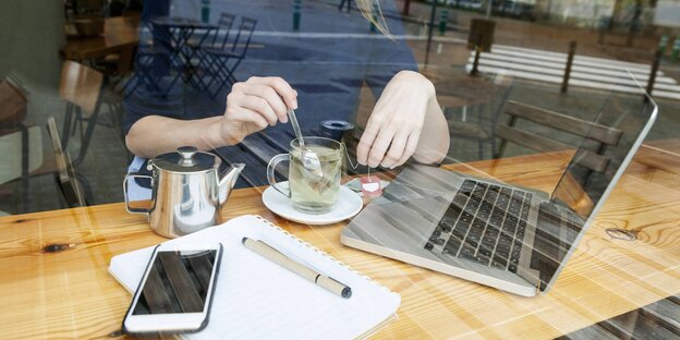 Eine Person arbeitet mit Laptop und Smartphone in einem Café Eine Person arbeitet mit Laptop und Smartphone in einem Café