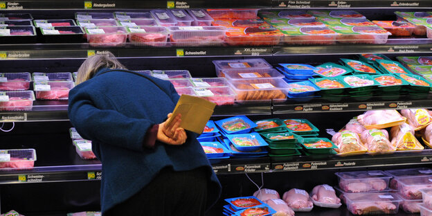 Frau steht vor vollem Einkaufsregal im Supermarkt Frau steht vor vollem Einkaufsregal im Supermarkt