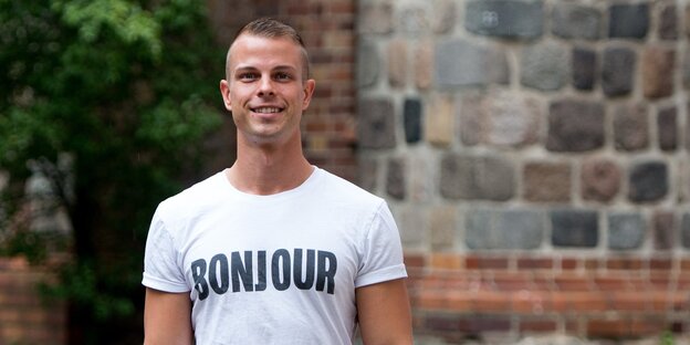 Ein Mann in weißem T-Shirt mit dem Aufdruck „Bonjour“ Ein Mann in weißem T-Shirt mit dem Aufdruck „Bonjour“