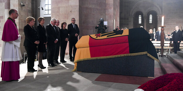 Ein mit deutscher Flagge umhüllter Sarg, davor stehen einige Menschen Ein mit deutscher Flagge umhüllter Sarg, davor stehen einige Menschen