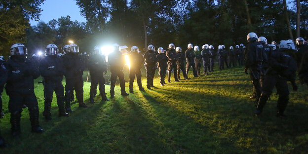 Polizisten stehen auf einer Wiese in der Reihe