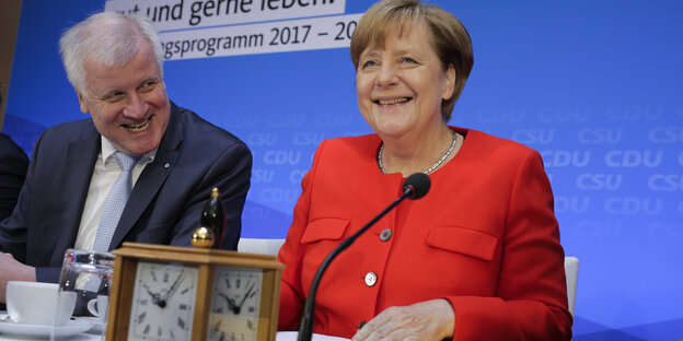 Seehofer und Merkel an einem Tisch mit Mikrofonen und einer Uhr Seehofer und Merkel an einem Tisch mit Mikrofonen und einer Uhr