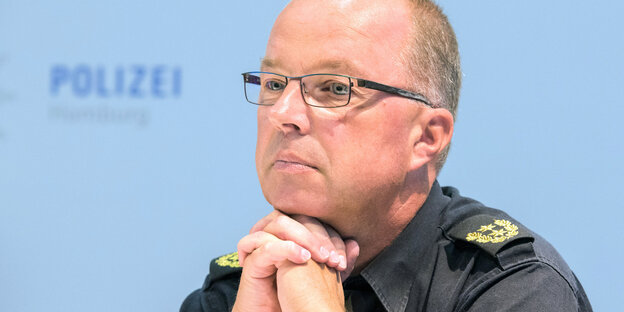 Ein Mann mit Brille stützt sein Kinn auf die gefalteten Hände Ein Mann mit Brille stützt sein Kinn auf die gefalteten Hände