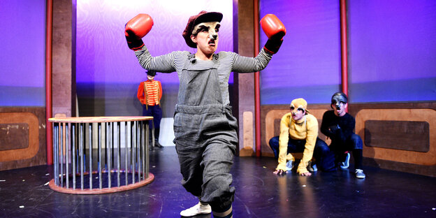 Ein Junge im Känguruhkostüm hebt auf einer Theaterbühne die Fäuste Ein Junge im Känguruhkostüm hebt auf einer Theaterbühne die Fäuste