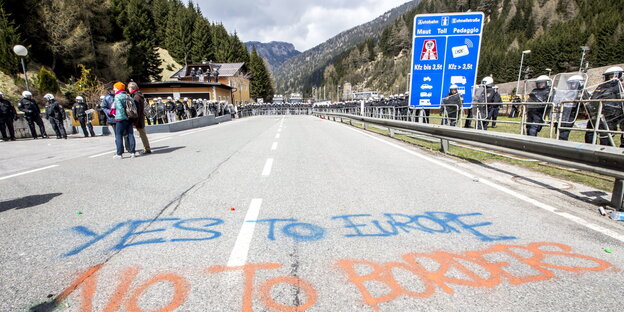 Ein Autobahnteilstück umstellt von Polizisten in Montur, mit Kreide draufgeschrieben: „Yes to Europe, No to Borders“ Ein Autobahnteilstück umstellt von Polizisten in Montur, mit Kreide draufgeschrieben: „Yes to Europe, No to Borders“