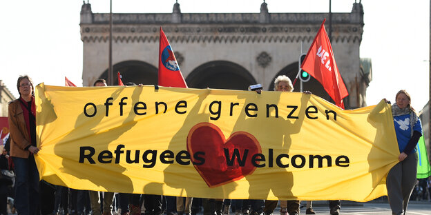 Demonstranten halten ein Plakat mit der Aufschrift "Offene Grenzen-Refugees welcome" hoch Demonstranten halten ein Plakat mit der Aufschrift "Offene Grenzen-Refugees welcome" hoch