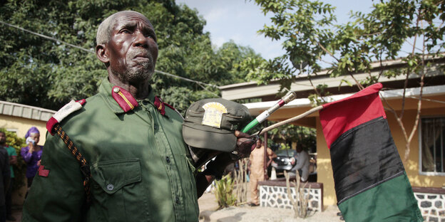 Ein Mann mit Uniform und der Biafra-Fahne in der Hand Ein Mann mit Uniform und der Biafra-Fahne in der Hand