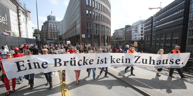 Demonstrierende halten ein Transparent in der Hand mit der Aufschrift "Eine Brücke ist kein Zuhause" Demonstrierende halten ein Transparent in der Hand mit der Aufschrift "Eine Brücke ist kein Zuhause"