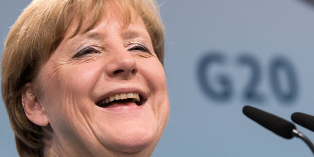 Angela Merkel lacht, im Hintergrund das G20-Logo Angela Merkel lacht, im Hintergrund das G20-Logo