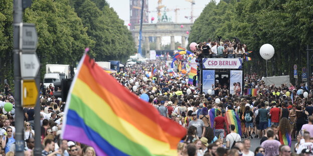 Eine Straße voller Menschen, zudem eine Regenbogen-Fahne Eine Straße voller Menschen, zudem eine Regenbogen-Fahne