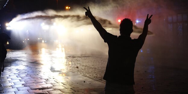 Ein Demonstrant steht im Scheinwerferlicht eines Wasserwerfers Ein Demonstrant steht im Scheinwerferlicht eines Wasserwerfers