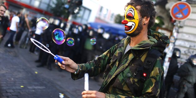 ein Mann mit Clownsmaske macht Seifenblasen auf der Straße ein Mann mit Clownsmaske macht Seifenblasen auf der Straße