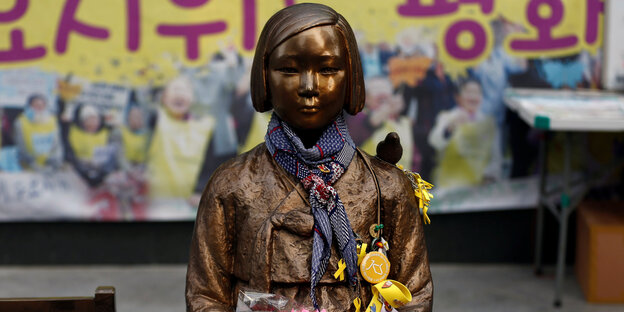 Die Statue einer Frau, der ein Vogel auf der Schulter sitzt Die Statue einer Frau, der ein Vogel auf der Schulter sitzt