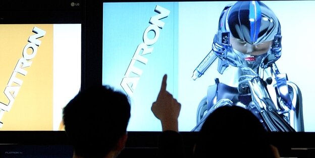 Menschen blicken auf einen Bildschirm, der einen weiblichen Roboter zeigt Menschen blicken auf einen Bildschirm, der einen weiblichen Roboter zeigt