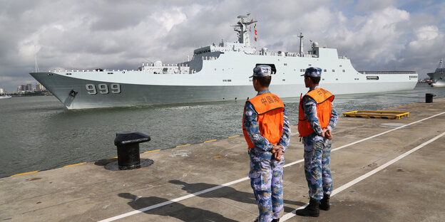 Zeri Hafenbearbeiter beobachten ein Militärschiff Zeri Hafenbearbeiter beobachten ein Militärschiff
