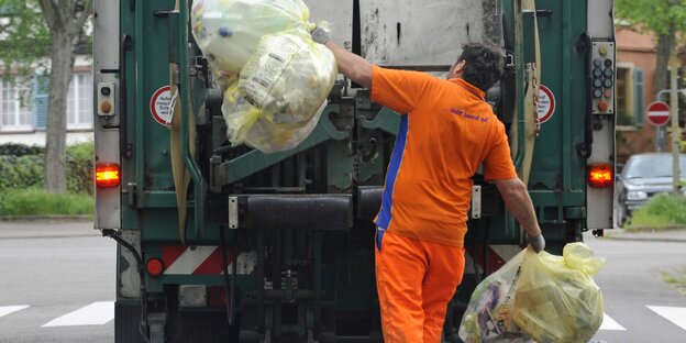 Ein Mann wirft Müll in den Müllwagen Ein Mann wirft Müll in den Müllwagen