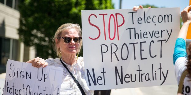 Eine Frau hält ein Schild hoch mit der Aufschrift "Stop Telekom Thievery, Protect Net Neutrality" Eine Frau hält ein Schild hoch mit der Aufschrift "Stop Telekom Thievery, Protect Net Neutrality"