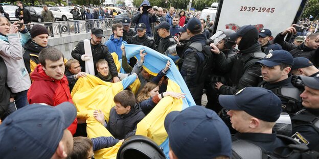 Menschen mit der ukrainischen Flagge in einer Menge aus Polizisten Menschen mit der ukrainischen Flagge in einer Menge aus Polizisten