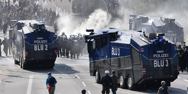 Wasserwerfer und Polizistehen stehen vor einer Demo