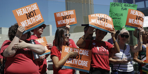 Menschen halten Schilder mit „Healthcare not Wealthcare“ in die Höhe. Menschen halten Schilder mit „Healthcare not Wealthcare“ in die Höhe.