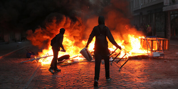 Zwei Menschen stehen vor einem Feuer auf der Straße