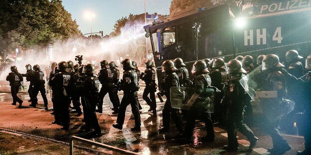 ein Trupp uniformierter Polizisten und ein Wasserwerfer