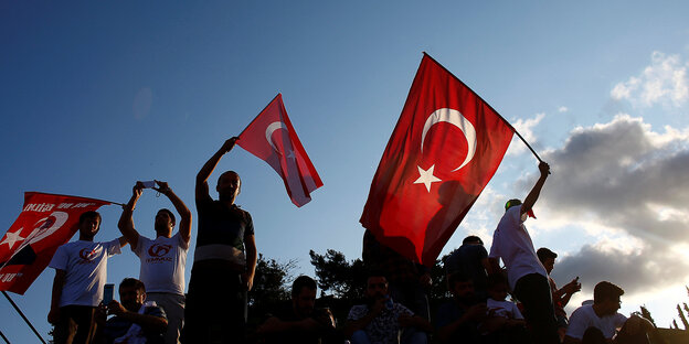 Menschen schwingen die türkische Fahne im Gegenlicht Menschen schwingen die türkische Fahne im Gegenlicht