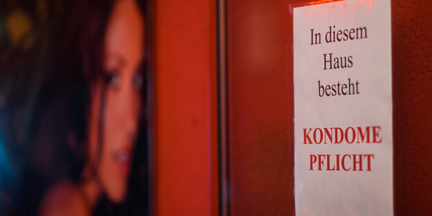 Schild an einer Tür. Darauf steht: In diesem Haus besteht Kondompflicht Schild an einer Tür. Darauf steht: In diesem Haus besteht Kondompflicht