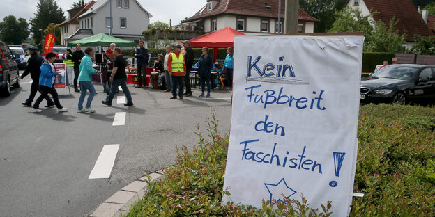 Auf einem Plakat steht „Kein Fußbreit den Faschisten“, dahinter Menschen und Sonnenschirme Auf einem Plakat steht „Kein Fußbreit den Faschisten“, dahinter Menschen und Sonnenschirme