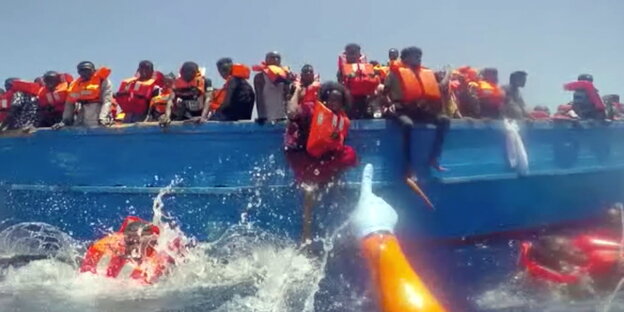 Menschen in Schwimmwesten auf einem kleinen Boot Menschen in Schwimmwesten auf einem kleinen Boot