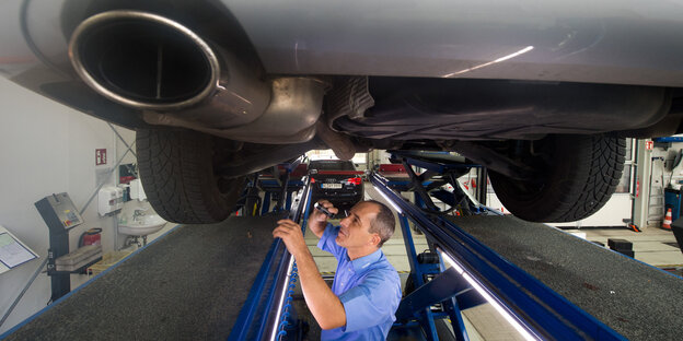 Ein Mann untersucht ein Auto Ein Mann untersucht ein Auto