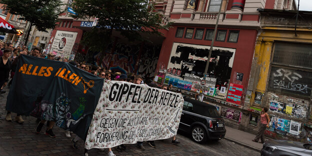 Menschen halten ein Banner und laufen vor einem Gebäude vorbei