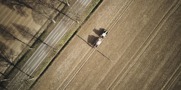 Vogelperpektive auf ein Feld, über das ein Traktor fährt Vogelperpektive auf ein Feld, über das ein Traktor fährt
