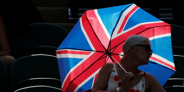 Eine Person hält einen Regenschirm, der aussieht, wie eine britische Flagge