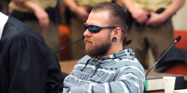 André Eminger mit Sonnenbrille, Kapuzenpulli und Ohrring sitzt im Gerichtssaal André Eminger mit Sonnenbrille, Kapuzenpulli und Ohrring sitzt im Gerichtssaal