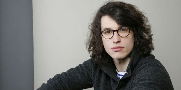 Der junge Zeichner trägt lange Haare und Brille. Der junge Zeichner trägt lange Haare und Brille.