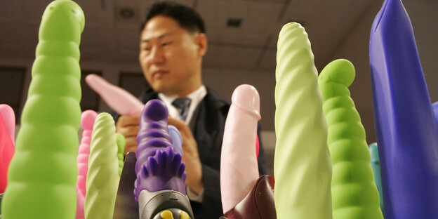 mehrere Vibratoren, im Hintergrund der Kopf eines Mannes mehrere Vibratoren, im Hintergrund der Kopf eines Mannes
