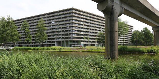 Ein grauer Beton-Wohnklotz vor einer saftig grünen Wiese