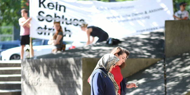 Kein Schlussstrich steht auf einem weißen Transparent, davor stehen Frauen und Männer Kein Schlussstrich steht auf einem weißen Transparent, davor stehen Frauen und Männer