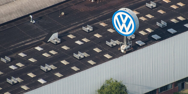 Ein Industriegebäude mit einem großen VW-Logo auf dem Dach aus der Vogelperspektive Ein Industriegebäude mit einem großen VW-Logo auf dem Dach aus der Vogelperspektive