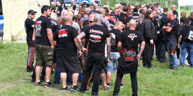 Kräftig gebaute Männer in schwarz-weiß-roten Band-T-Shirts stehen auf einer Wiese Kräftig gebaute Männer in schwarz-weiß-roten Band-T-Shirts stehen auf einer Wiese