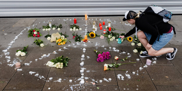 Eine Frau legt Blumen auf den Boden