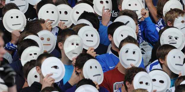 Menschen halten weiße Masken vor ihren Gesichtern Menschen halten weiße Masken vor ihren Gesichtern