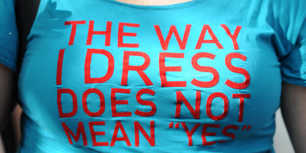 Eine Person trägt ein T-Shirt mit dem Aufdruck "The Way I Dress Does not Mean 'Yes'" Eine Person trägt ein T-Shirt mit dem Aufdruck "The Way I Dress Does not Mean 'Yes'"